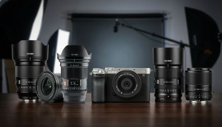A collection of Viltrox lenses on a table in a photo studio setting, one of them is attached to a Sony A7 C. Background generated by Gemini
